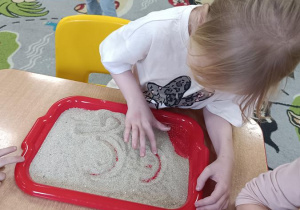 Dzieci podejmują próby pisania na piasku