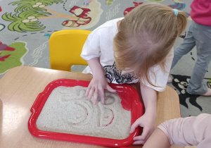 Dzieci podejmują próby pisania na piasku