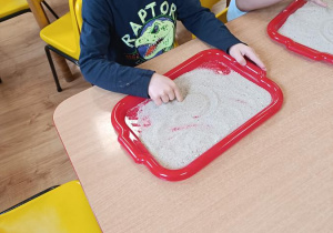 Dzieci podejmują próby pisania na piasku