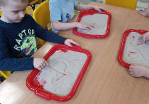 Dzieci podejmują próby pisania na piasku