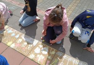 Dzieci rysują kredą łąkę na tarasie.