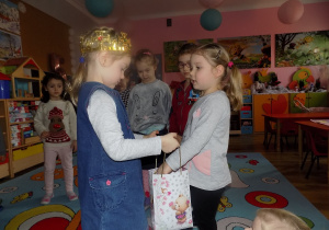 Gabrysia częstuje Marysię urodzinowym cukierkiem.