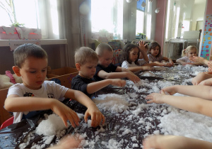 Dzieci w czasie zabawy sztucznym śniegiem.