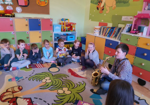 Dzieci słuchają gry na saksofonie.