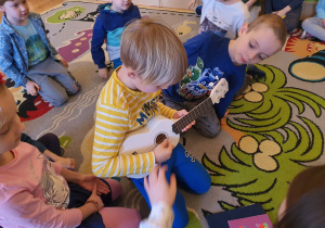 Szymek gra na ukulele.