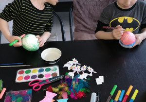 Wojtuś starannie maluje jajko a Szymek zerka co rysuje starszy brat. Może na swojej też tak narysuje.