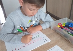 Filip ćwiczy pisanie literki f jak flaga.