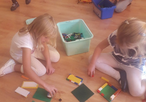 Dziewczynki budują z kolocków lego.