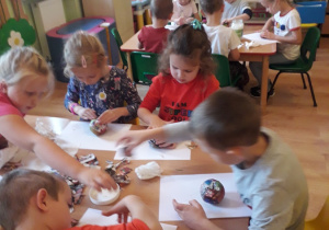Dzieci kleją jabłka z masy papierowej.