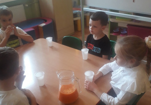 Dzieci piją sok marchewkowy.