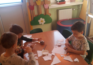 Dzieci kleją jabłka z masy papierowej.