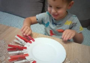 Tomek przyczepia do talerzyka-spinacze do bielizny(w kolorze białym i czerwonym)
