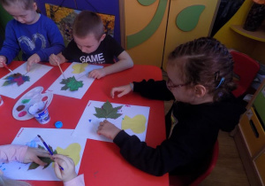 Zosia, Arthur i Lena pracują przy stoliku.