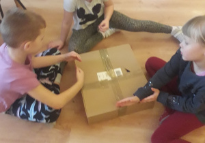 Dzieci mierzą długość pudełka dłonią..