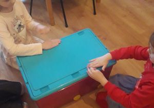 Dzieci mierzą długość pudełka dłonią..