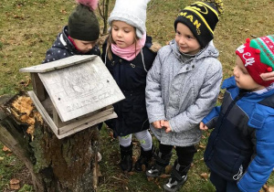 Mateusz, Adam, Nikola i Zosia przy karmniku dla ptaków.