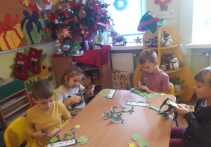 Dzieci wycinają kółka do wykonania choinki techniką origami.