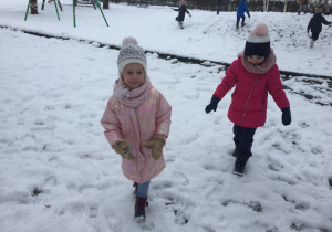 Hania J, Hania D spacerują w ogrodzie przedszkolnym.