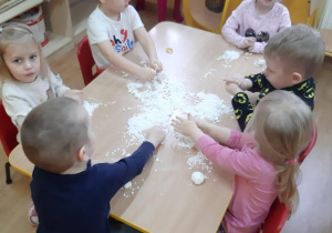 Kornelia wraz z kolegami i koleżankami lepi bałwanki.