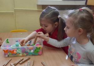 Zosia i Kornelia ćwiczą nakładanie pokarmu dla ptaków.