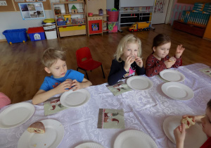 Hubert, Hania i Róża smakują pyszne pączki.