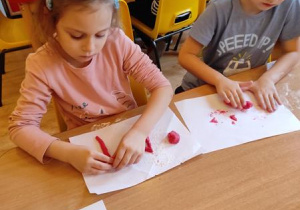 Natalka i Filip R. lepią z masy solnej samogłoski.